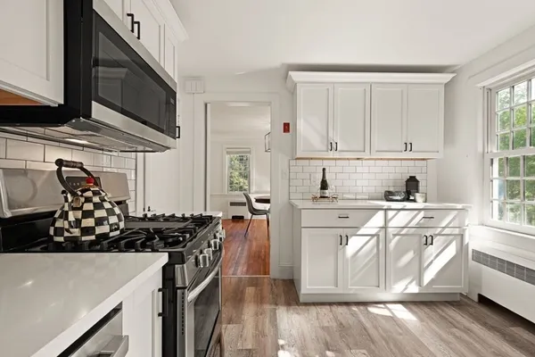 a kitchen with stainless steel appliances a stove a sink and white cabinets