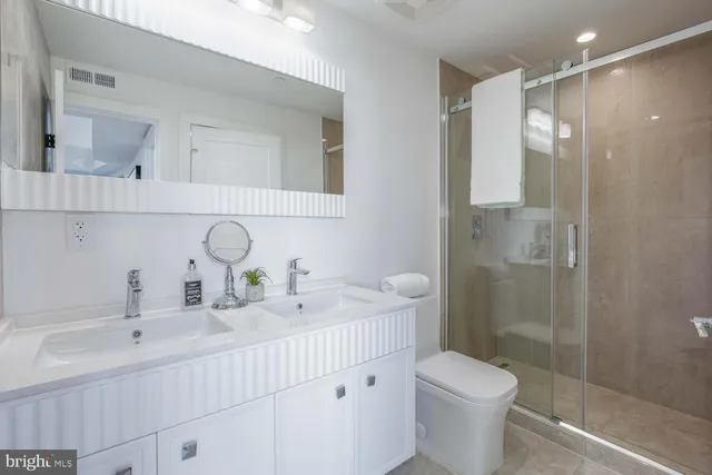 a bathroom with a double vanity sink toilet and shower