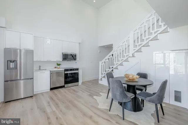 a kitchen with stainless steel appliances a white table and chairs