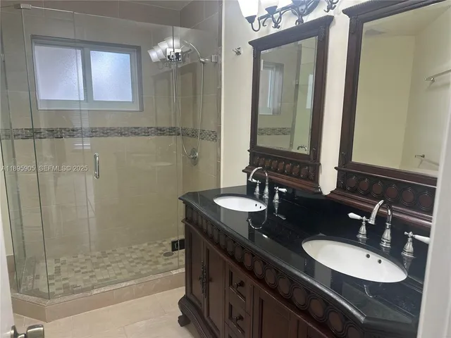 a bathroom with a double vanity sink mirror and shower