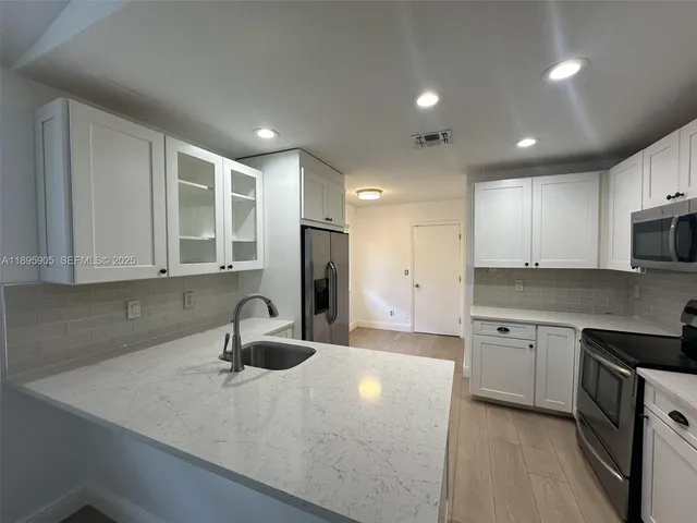 a kitchen with granite countertop a sink a stove and cabinets