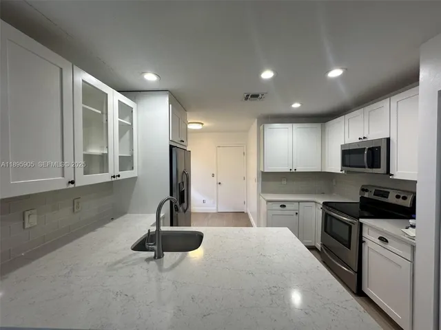 a kitchen with stainless steel appliances a sink stove and cabinets