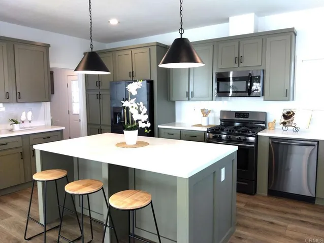 a kitchen with stainless steel appliances kitchen island a table and chairs in it