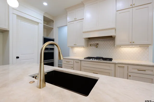 a kitchen with granite countertop a stove a sink and a refrigerator