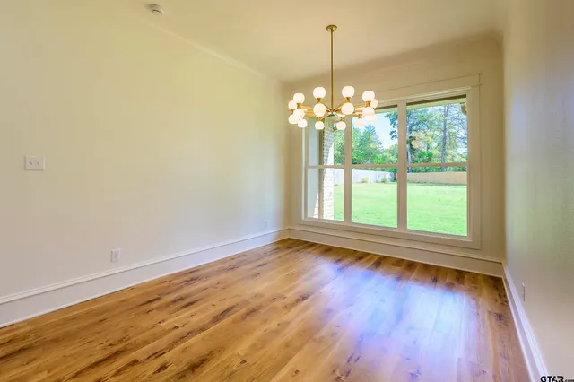 a view of a room with wooden floor chandelier and a window