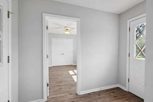 a view of an empty room with wooden floor and a window