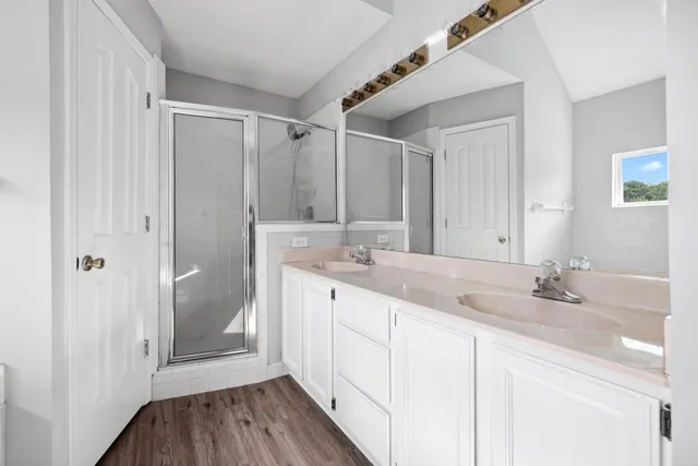 a bathroom with a double vanity sink and mirror with shower