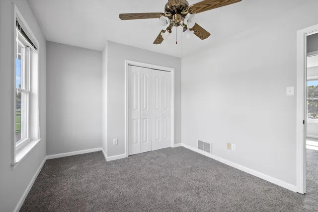 an empty room with a window and a fan