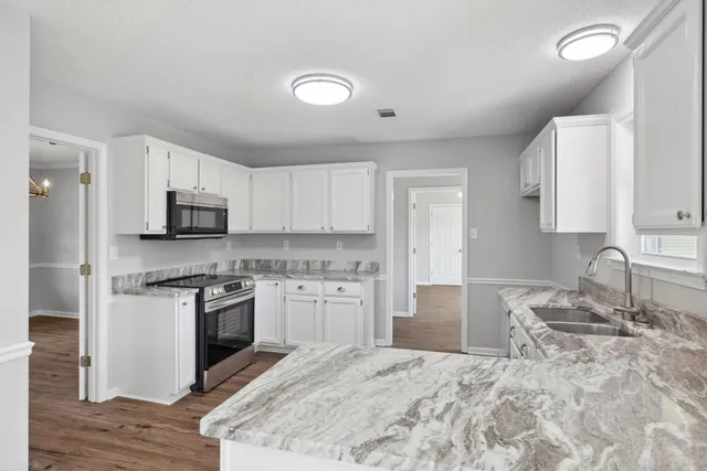 a kitchen with granite countertop a stove top oven sink and cabinets