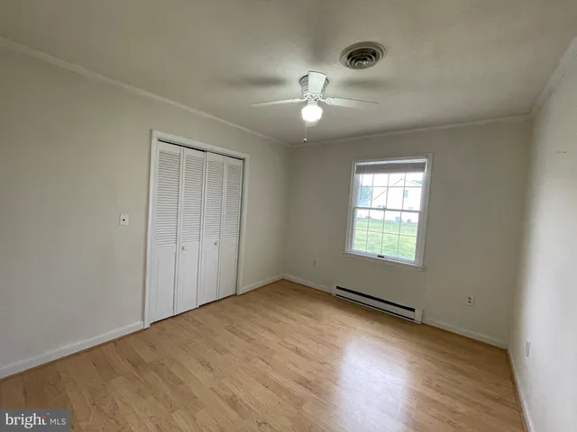 an empty room with a window and chandelier fan