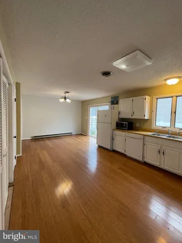 a view of a kitchen with kitchen island wooden floors and stainless steel appliances