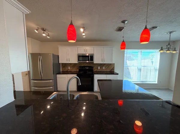 a kitchen with granite countertop a refrigerator and a stove top oven