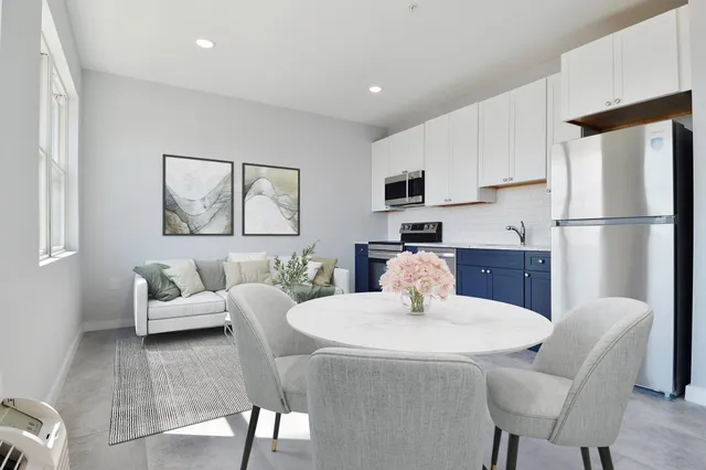 a kitchen with stainless steel appliances granite countertop a dining table chairs and a refrigerator