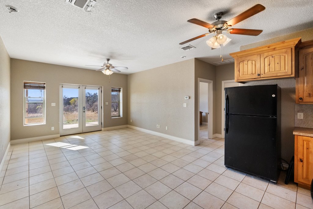 1101 Crider Road Marble Falls, TX 78654 - Photo 32 of 34 Kitchen featuring freestanding refrigerator, ceiling fan, a textured ceiling, light tile patterned flooring, and light countertops