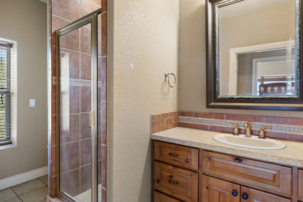 1101 Crider Road Marble Falls, TX 78654 - Photo 34 of 34 Full bathroom featuring a textured wall, a shower stall, vanity, and light tile patterned flooring