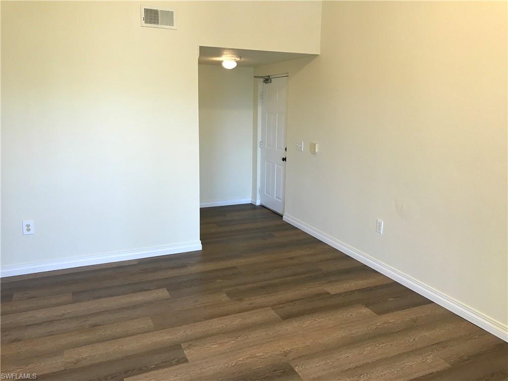 7985 Preserve Circle, Unit 1133 Naples, FL 34119 - Photo 13 of 36 a view of an empty room with wooden floor