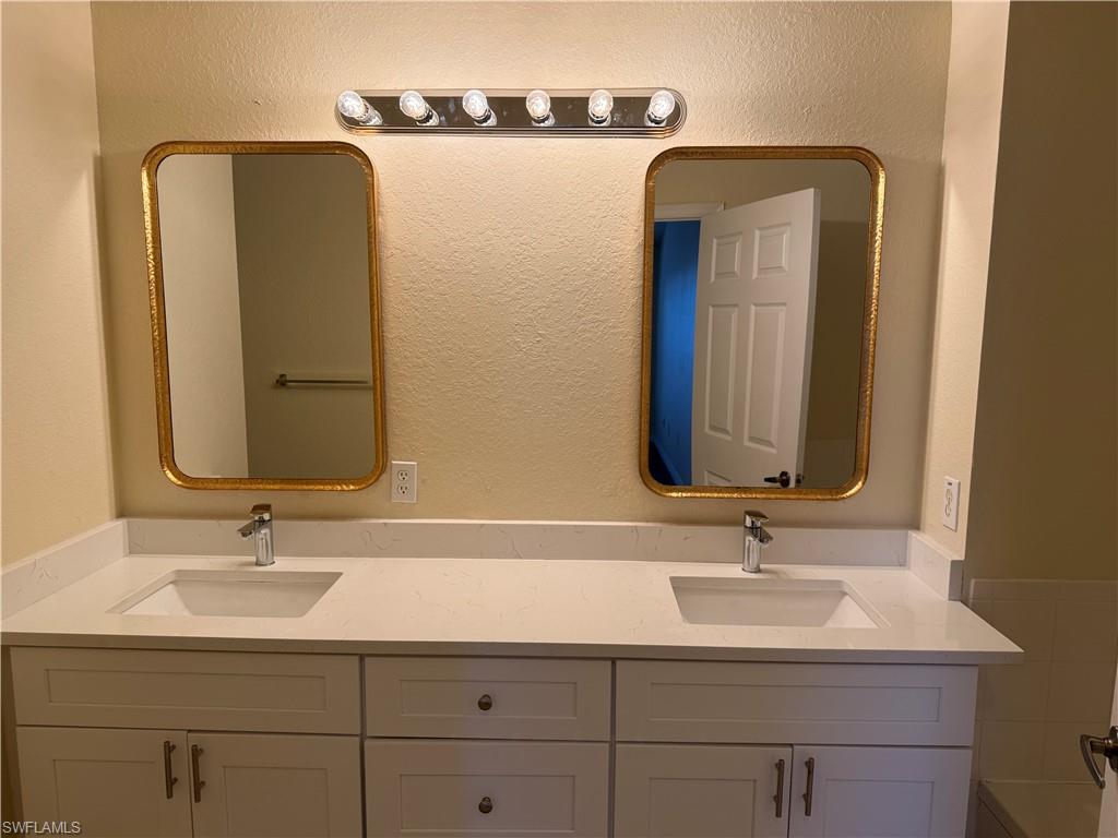 7985 Preserve Circle, Unit 1133 Naples, FL 34119 - Photo 18 of 36 Full bathroom with double vanity and a textured wall