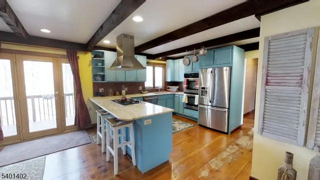 a kitchen with stainless steel appliances granite countertop a refrigerator a stove and a wooden floors