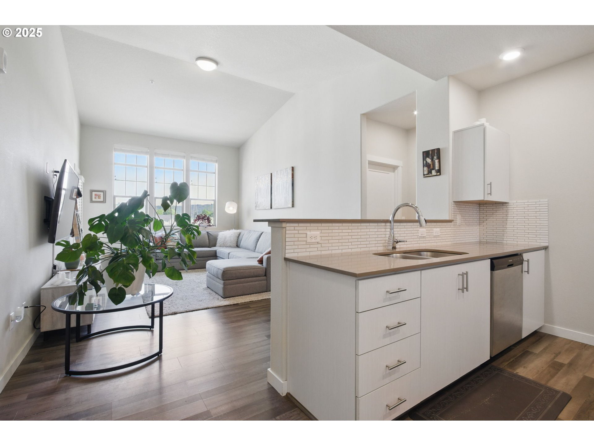 16322 Northwest Chadwick Way, Unit 303 Portland, OR 97229 - Photo 5 of 23 a living room with kitchen island furniture a potted plant and a sink