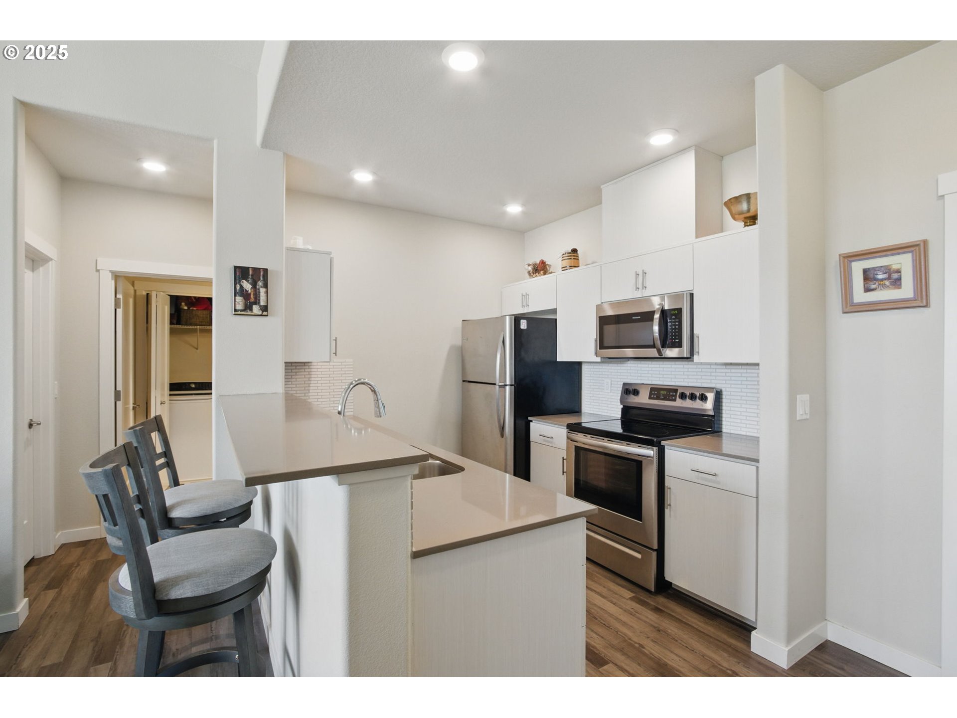 16322 Northwest Chadwick Way, Unit 303 Portland, OR 97229 - Photo 6 of 23 a kitchen with stainless steel appliances granite countertop a refrigerator a stove top oven a sink dishwasher and white cabinets with wooden floor