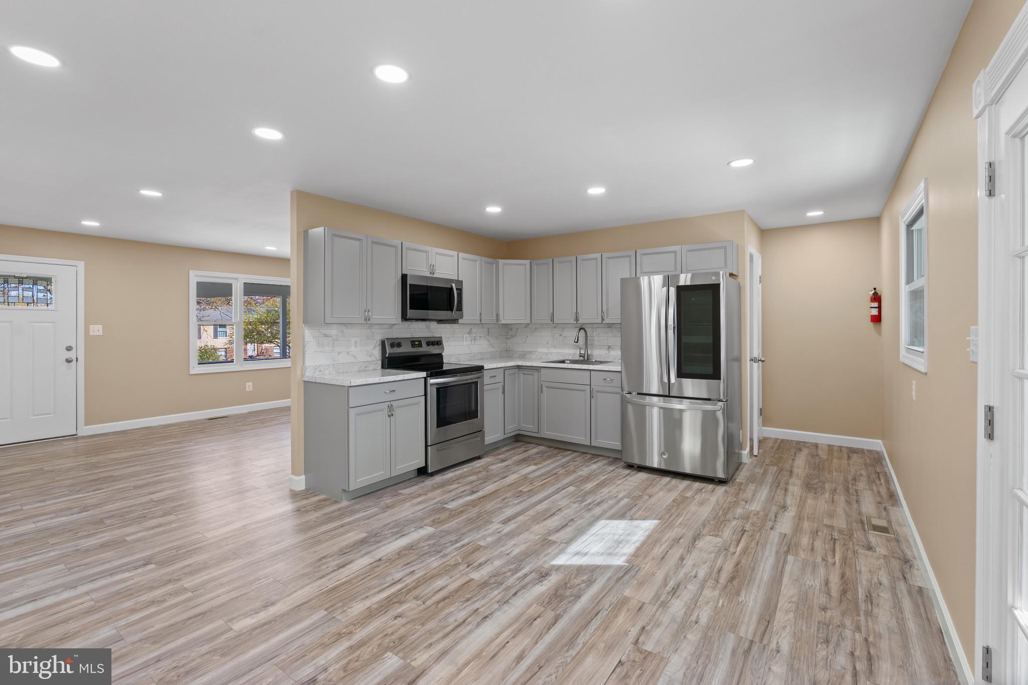 712 Kent Avenue Baltimore, MD 21228 - Photo 8 of 30 a kitchen with granite countertop a refrigerator oven a sink dishwasher and white cabinets with wooden floor