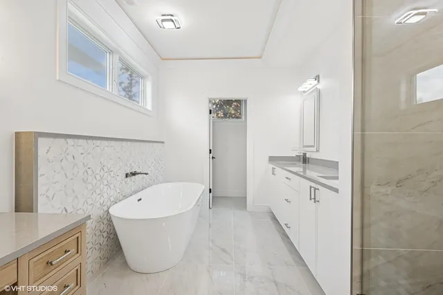 a spacious bathroom with a double vanity sink a mirror and a bathtub