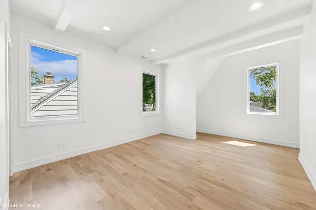 a view of empty room with wooden floor and kitchen