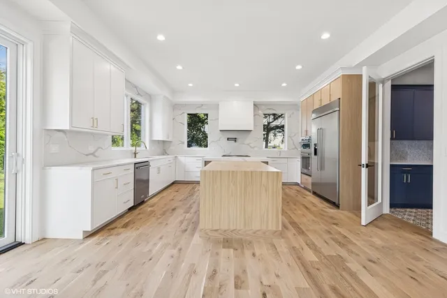 a large white kitchen with a stove a sink dishwasher and a refrigerator with wooden floor