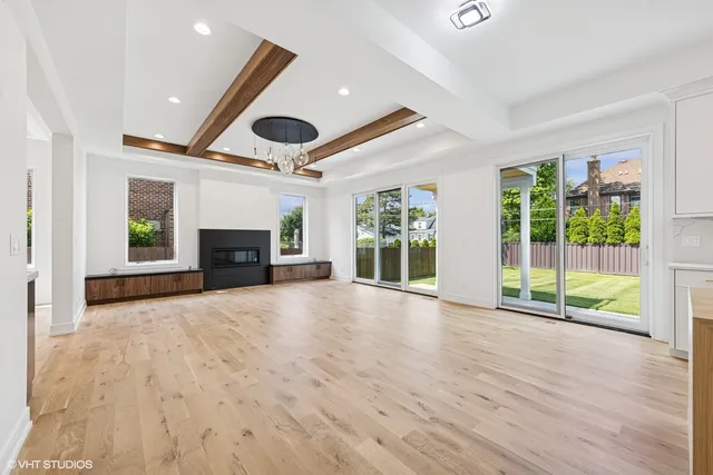 a view of an empty room with wooden floor and a fireplace