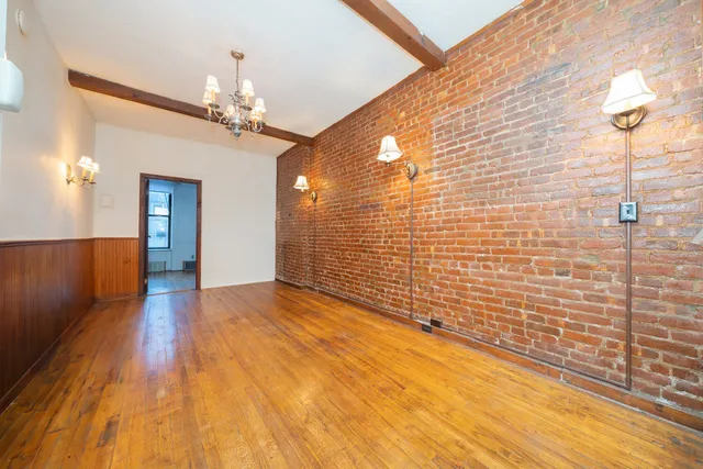 a view of a hallway with wooden floor and chandelier