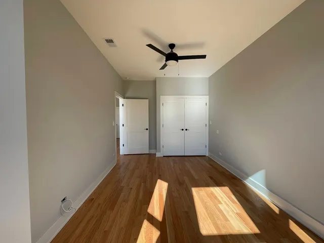 an empty room with wooden floor cabinet and windows