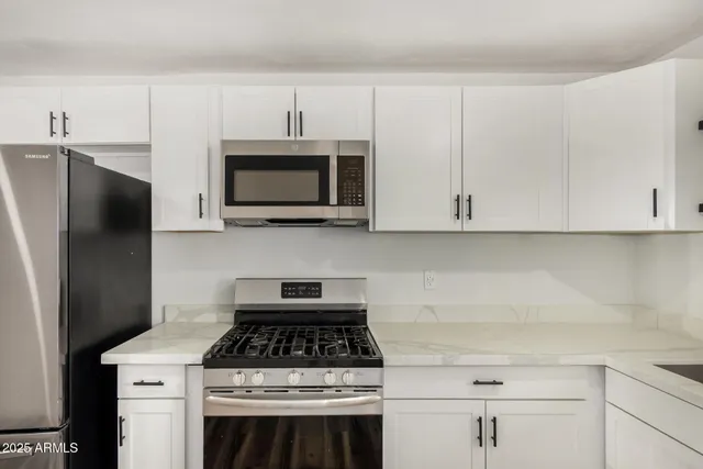 a kitchen with stainless steel appliances white cabinets and a stove top oven