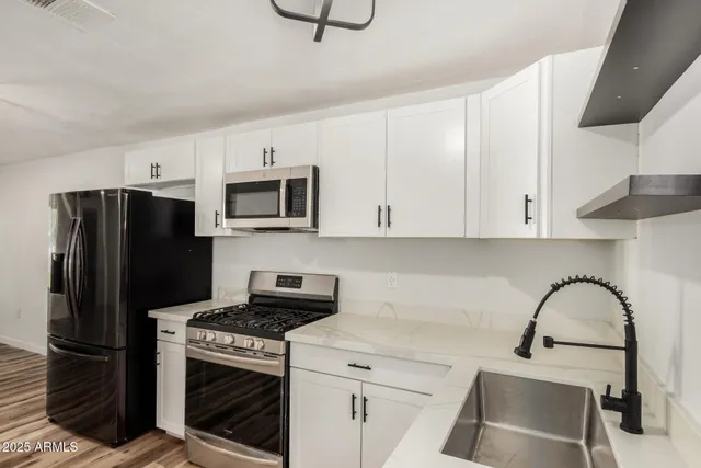 a kitchen with stainless steel appliances granite countertop a refrigerator sink and stove