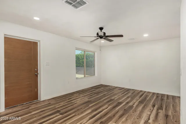 a view of empty room with wooden floor and fan