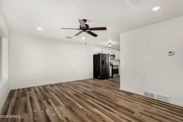 a view of an empty room with a ceiling fan window and a ceiling fan