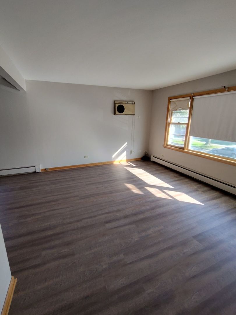7824 West Addison Street, Unit 2 Chicago, IL 60634 - Photo 11 of 28 an empty room with wooden floor and windows
