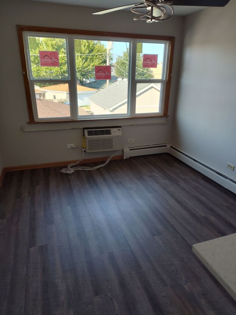 7824 West Addison Street, Unit 2 Chicago, IL 60634 - Photo 8 of 28 an empty room with wooden floor and windows