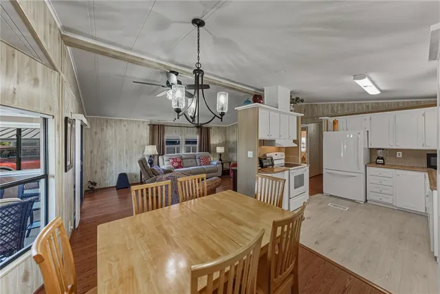 a kitchen with stainless steel appliances kitchen island granite countertop a refrigerator a stove top oven a sink dishwasher and white cabinets with wooden floor