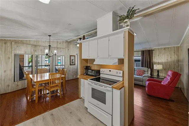 a kitchen with stainless steel appliances kitchen island granite countertop a stove a refrigerator and a dining table with wooden floor