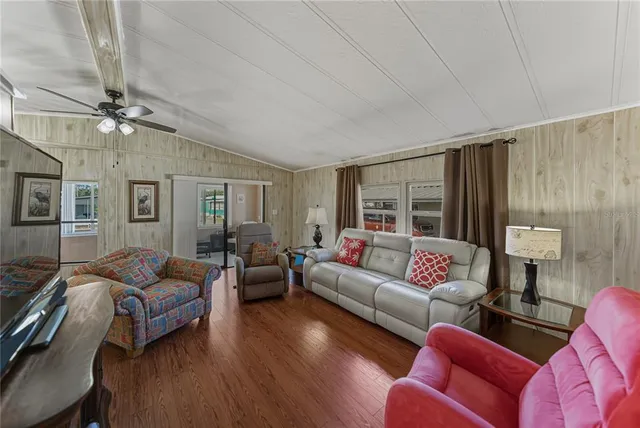 a living room with furniture ceiling fan and a wooden floor