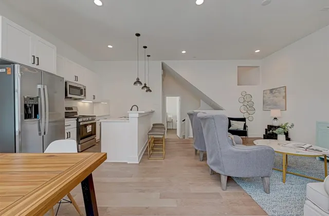 a living room with stainless steel appliances furniture a rug and a kitchen view