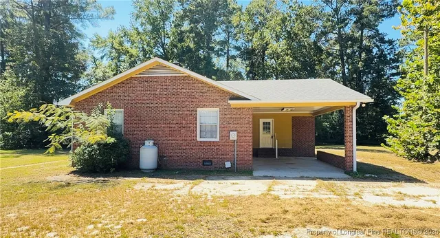 a backyard of a house with table and chairs under an umbrella