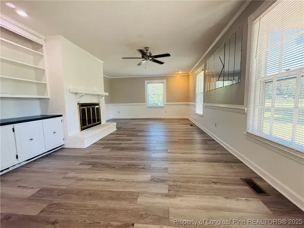 wooden floor in an empty room with a fireplace and a window
