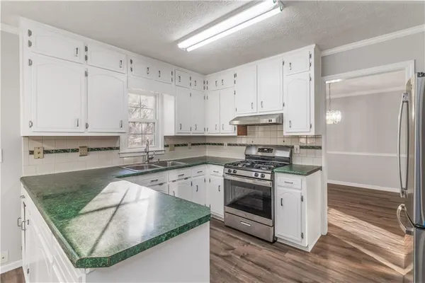 a kitchen with stainless steel appliances granite countertop a stove a sink and a microwave