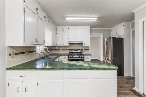 a kitchen with stainless steel appliances granite countertop a sink a refrigerator and a granite counter tops