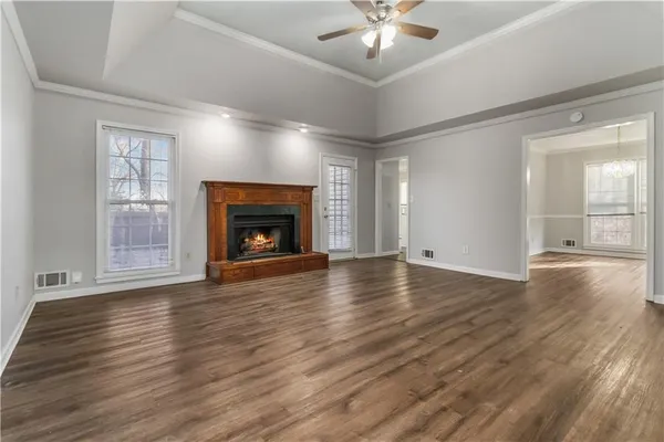a view of an empty room with wooden floor fireplace and a window