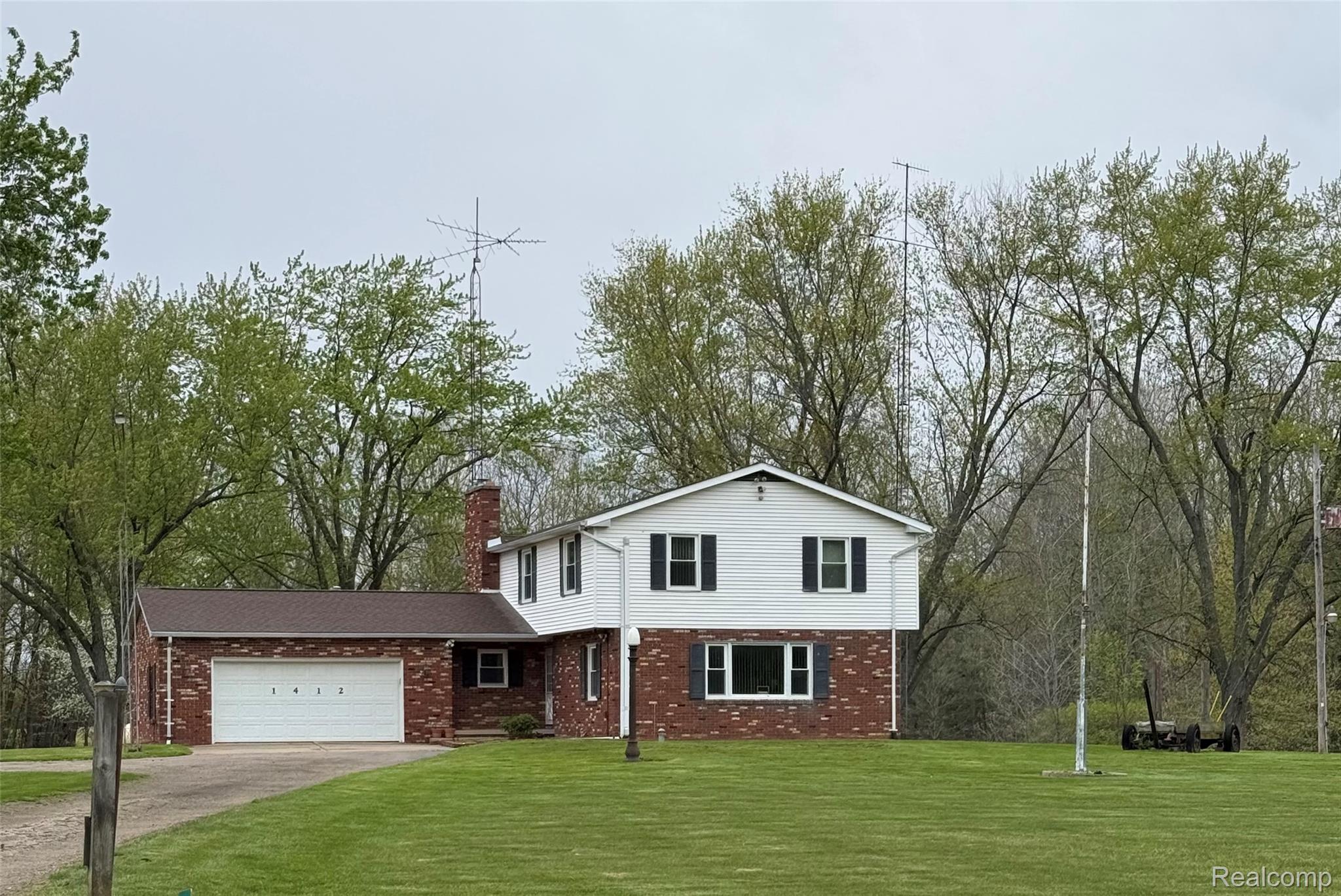 1412 South Byron Road Lennon, MI 48449 - Photo 1 of 22 Traditional-style house featuring brick siding, a front lawn, driveway, an attached garage, and a chimney