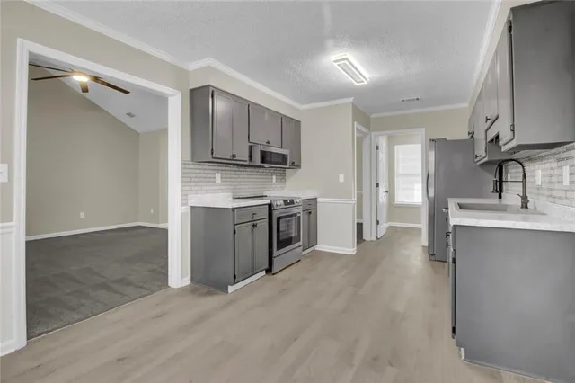 a kitchen with stainless steel appliances a sink dishwasher a refrigerator and a stove top oven