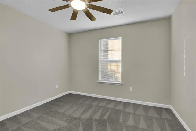 an empty room with a window and a fan