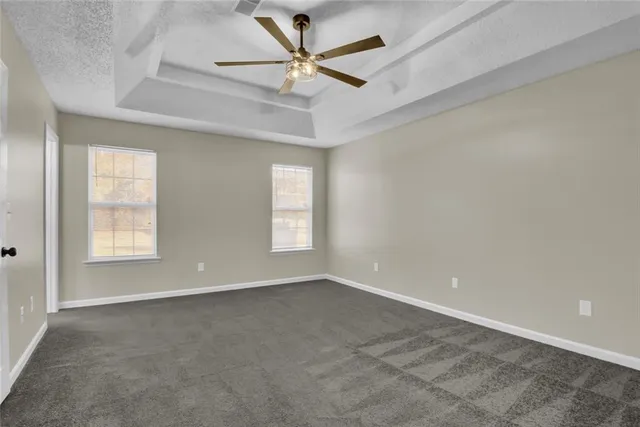 an empty room with a chandelier fan and windows